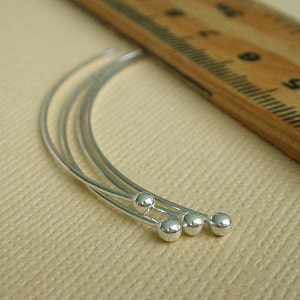 May include: A set of three silver bangle bracelets with rounded ends. The bracelets are stacked on top of each other.