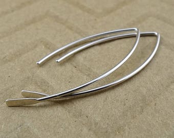 Puede incluir: Un par de pendientes de aro de plata con un diseño simple y curvo. Los pendientes están hechos de alambre fino y tienen un aspecto delicado y minimalista.