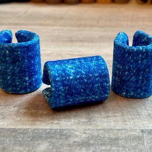 Puede incluir: Tres férulas azules para dedos con un patrón moteado. Las férulas son cilíndricas con una abertura curva en la parte superior. Están diseñadas para sostener y proteger los dedos. Las férulas están hechas de un material flexible.