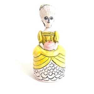 Puede incluir: Un juego de tres botes de cerámica con tapas. Los botes son blancos con un estampado floral azul. El más grande mide 20 cm de alto, el mediano 18 cm y el más pequeño 15 cm.