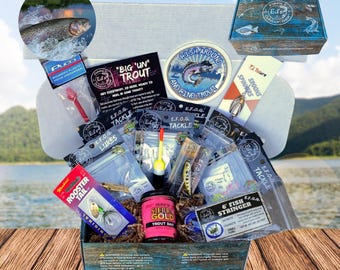 Puede incluir: Una caja de madera llena de equipo de pesca, incluyendo señuelos, spinners, un porta-pescado y un frasco de cebo para truchas. La caja está decorada con un diseño azul y blanco y el texto "Ed's Quality Gear".
