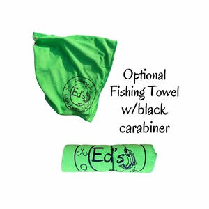 May include: Green fishing towel with a black carabiner. The towel has a black circle logo with the text "Fishing & Ed's Outdoor Gear".