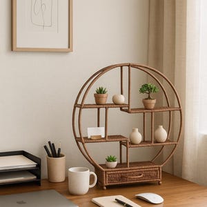 Pode incluir: Uma prateleira redonda de vime tecido com v&aacute;rias prateleiras, com pequenas plantas em vasos e vasos decorativos. A unidade est&aacute; em uma mesa de madeira com um laptop, teclado e outros materiais de escrit&oacute;rio. Uma obra de arte abstrata emoldurada est&aacute; pendurada na parede.
