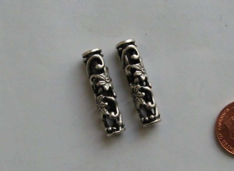 May include: Two silver metal bead spacers with a floral design. The spacers are about 1 inch long.