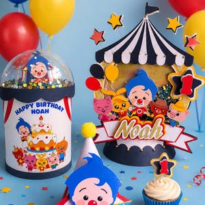 May include: A festive birthday scene with balloons, a cupcake, and decorative elements. The centerpiece features a circus-themed design with the name "Noah" and a "Happy Birthday" message. Colorful stars and confetti add to the celebratory atmosphere.