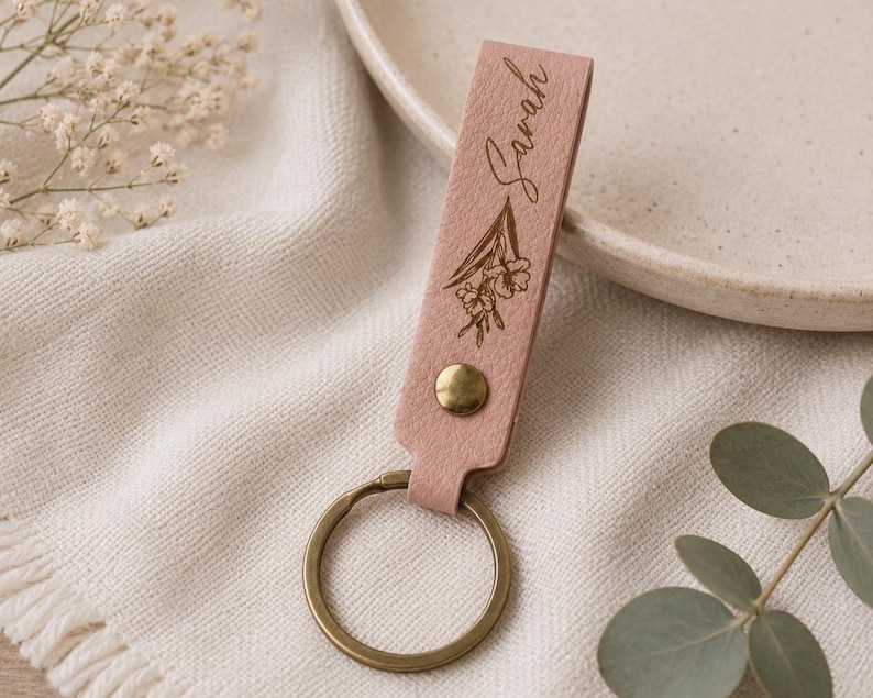 Custom name leather keychain with engraved birth flower and durable metal key ring. The handcrafted leather accessory is beautifully packaged and ready to give as a meaningful personalized gift.