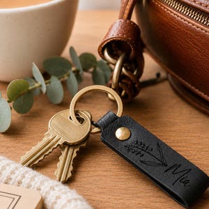 Personalized leather keychain packaged on a kraft backing card inside a clear gift sleeve with a satin ribbon. Gift-ready presentation with botanical details and durable brass hardware.