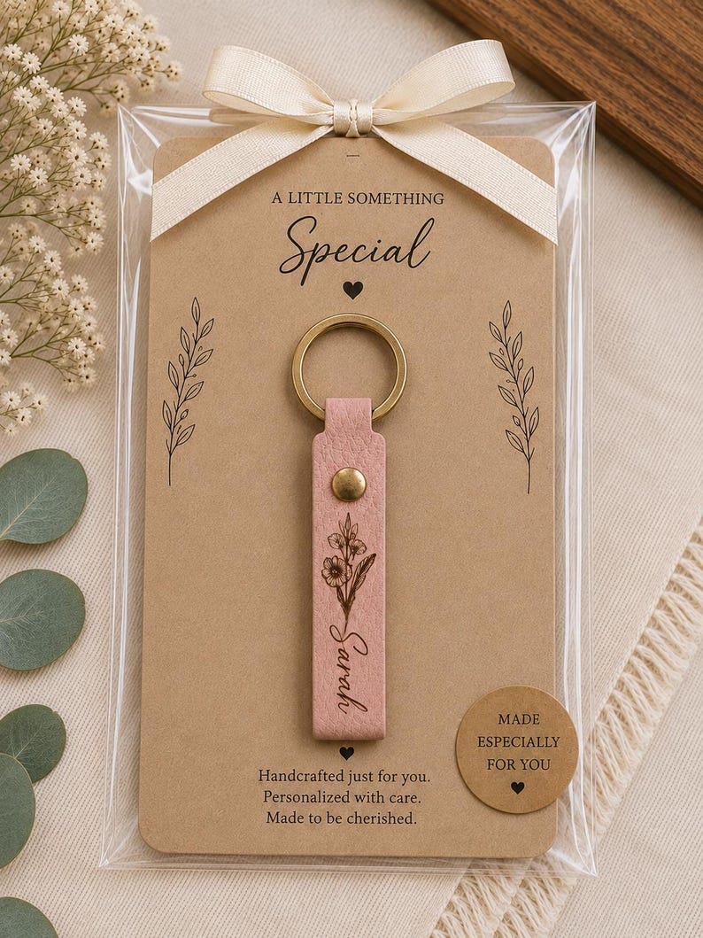 Engraved leather keychain featuring a personalized name surrounded by a delicate botanical birth flower design. Premium leather and brass hardware create an elegant everyday accessory.