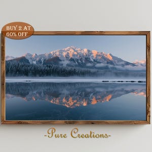 May include: A photograph of a mountain range reflected in a still lake. The mountains are covered in snow and the sky is a soft blue. The reflection of the mountains in the lake is clear and crisp.