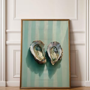 May include: A framed artwork featuring two open oyster shells against a teal and white striped background. The artwork is displayed in a room with white doors and a wooden floor.