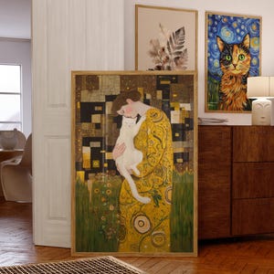 Può includere: Una stampa artistica incorniciata raffigurante una donna in abito giallo che tiene un gatto bianco. L'opera d'arte presenta un design dorato e geometrico. Sono visibili altre opere d'arte incorniciate, tra cui un ritratto di gatto e una stampa botanica.