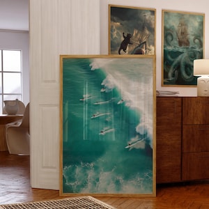 May include: A framed print of surfers riding a large ocean wave. The water is a vibrant turquoise color, with white foam from the breaking wave. Several other framed art pieces are visible in the background.
