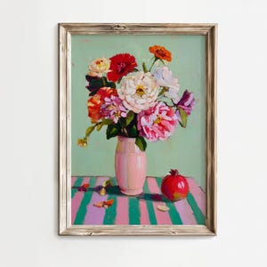 Op de afbeelding: Een ingelijst bloemstilleven schilderij. Een roze vaas bevat een boeket van rode, witte en roze bloemen. Een rode granaatappel ligt op een tafel met roze en groene strepen. De achtergrond is lichtgroen.
