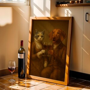 Op de afbeelding: Een vintage schilderij in een lijst van een kat en een hond die proosten met wijnglazen. Een fles rode wijn en een wijnglas staan voor het schilderij. Het schilderij en de wijn staan op een betegelde vloer, bij een raam.
