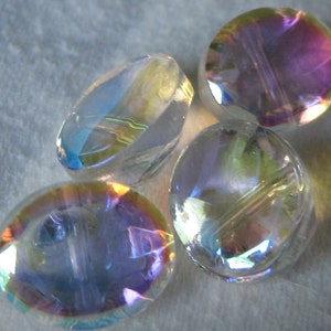 May include: Four iridescent glass beads with a hole through the center. The beads are oval shaped and have a rainbow sheen.