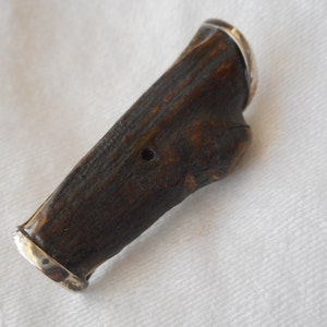 May include: A dark brown wooden handle with a silver band at each end. The handle has a small hole in the center.