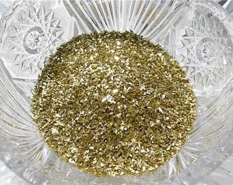 May include: A clear glass bowl filled with gold glitter. The glitter is made up of small, irregular pieces of gold foil.
