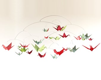 May include: A mobile with red and green origami paper cranes hanging from a wire frame. The cranes are suspended at different heights and angles, creating a dynamic and whimsical display.