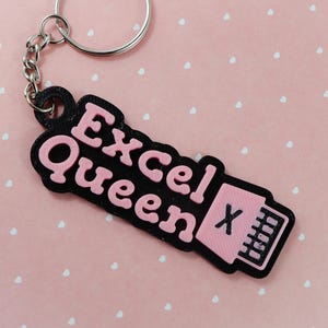 May include: Black keychain with the text "Excel Queen" in pink letters and a pink Excel icon with a white "X".