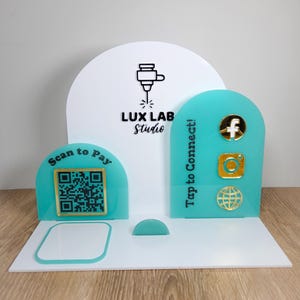 Puede incluir: Un expositor de acrílico blanco y turquesa con el texto "LUX LAB Studio". El expositor presenta un código QR para el pago, iconos de redes sociales y el texto "Tap to Connect!".