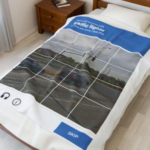 Może przedstawiać: Biały koc z niebieską obwódką przedstawiający scenę drogową z samochodami i światłami drogowymi, z siatką. Tekst brzmi: "Zaznacz wszystkie kwadraty ze światłami drogowymi, jeśli nie ma żadnych, kliknij pomiń".