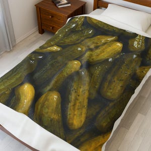 May include: A bedspread with a close-up image of many pickles. The pickles are a vibrant green and yellow colour, with a glossy appearance. The bedspread is on a bed with a white pillow and a wooden bedside table.