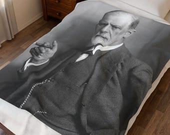 Puede incluir: Una manta en blanco y negro con un retrato de un hombre distinguido con traje, sosteniendo un bolígrafo. La imagen es un primer plano de la parte superior del cuerpo del hombre, con un enfoque en su rostro y vestimenta. La manta está sobre una cama.