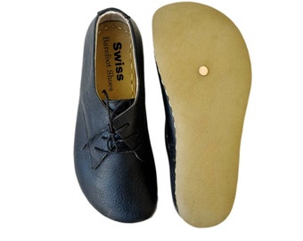 May include: A pair of black leather lace-up shoes with a brown leather sole. The shoes have the text "Swiss Barefoot Shoes" printed on the inside of the shoe.