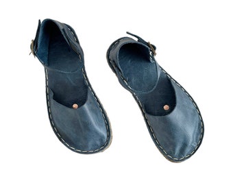 Puede incluir: Un par de sandalias de cuero azul con cierre de hebilla. Las sandalias tienen un diseño sencillo y están hechas de cuero suave y flexible.