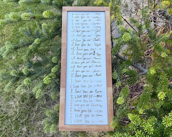 May include: A rectangular wooden frame containing a white board with the repeated handwritten phrase I love you so followed by various names including Kaidyn, Carter, Lanny, Joel, Jessi, Dadd, Wyatt, Q, Izzy, Noomi, Deacon, Annett, Jonah, Heidi, Oliver, Pace, Cewon, Kami, Neal, Courtney, Elle, Emma, and Etta.