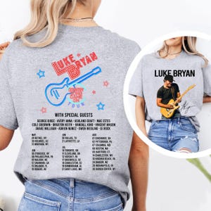 May include: Gray t-shirt featuring the text "LUKE BRYAN" in red and white, with a guitar graphic and tour dates. The back of the shirt has a photo of Luke Bryan playing a guitar. Special guests are listed.
