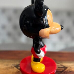 K&ouml;nnte beinhalten: Eine schwarze und rote Mickey Mouse Figur mit gl&auml;nzender Oberfl&auml;che. Die Figur steht auf einem roten Sockel.