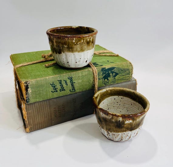 Wheel-thrown stoneware cups with that tactile, one-of-a-kind studio pottery feel — the kind of object that makes morning coffee feel deliberate.