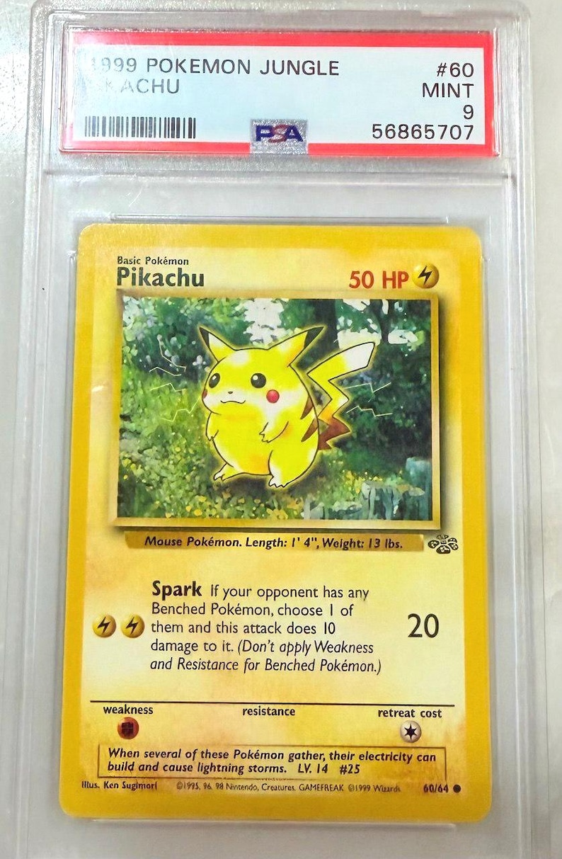 May include: A graded 1999 Pok&eacute;mon Jungle Pikachu card. The card features a yellow Pikachu illustration with the text "Pikachu" and "50 HP". The card is in a protective case with a label that reads "#60 MINT 9".