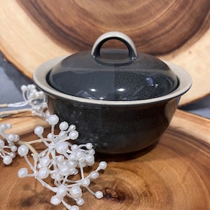 Könnte beinhalten: Eine schwarze und weiße Zuckerdose aus Keramik mit Deckel und Henkel. Die Schüssel hat ein geometrisches Muster.