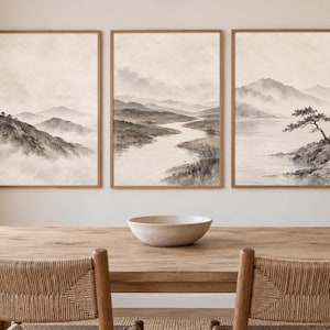 May include: A triptych of framed wall art prints featuring monochromatic landscape scenes in shades of beige, cream, and charcoal gray. The images depict misty mountain ranges, a winding river valley, and a solitary tree by a calm lake.