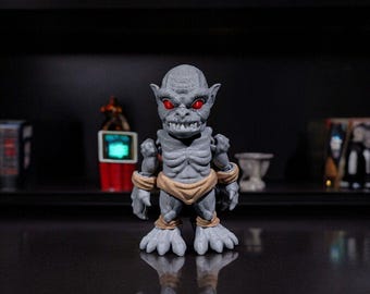 May include: A gray and brown figurine of a monster with red eyes. The monster is standing on a black surface.