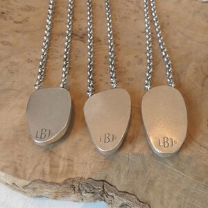May include: Three silver necklaces featuring smooth, irregular, pebble-shaped pendants suspended from thick, round link chains. Each pendant is stamped with the letters LBJ and the number 925, indicating sterling silver composition.
