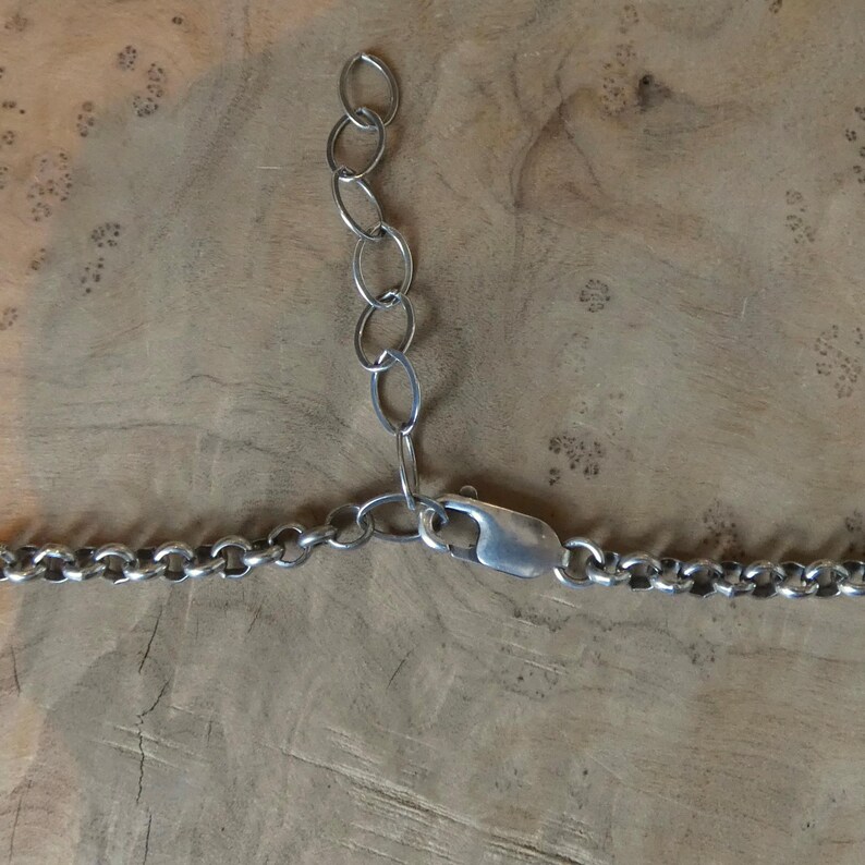 May include: A silver-toned metal chain necklace featuring a series of round interlocking links. The necklace includes a lobster claw clasp and an adjustable extender chain consisting of five larger oval links for varying the length of the piece.