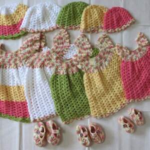 May include: Four crocheted baby dresses in pink, yellow, green, and white with matching crocheted hats and shoes.