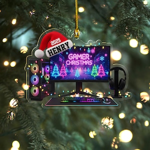 May include: A Gamer Christmas ornament featuring a computer setup with a monitor, keyboard, and headphones. The ornament includes a red Santa hat with the name "HENRY" and the year "2025". The words "GAMER CHRISTMAS" are displayed on the monitor.