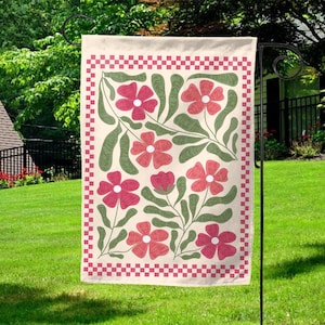 May include: A rectangular garden flag with a floral design. The flag features a cream-colored background with a red and white checkered border. The design includes red flowers and green leaves.