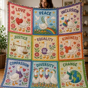 May include: A quilted blanket featuring nine panels with white ducks and the words Love, Peace, Inclusion, Justice, Equality, Kindness, Compassion, Diversity, and Change. Each square displays colorful floral accents, hearts, stars, and rainbows.