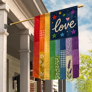 May include: A colorful outdoor flag with a patchwork design. The flag features a rainbow of colors and patterns, with the word "love" in cursive script. Stars and hearts decorate the dark blue top section. The flag is hanging from a wooden pole.