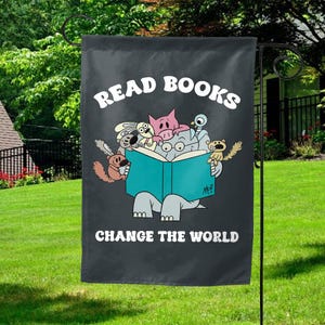 May include: A black garden flag with the text "Read Books Change The World" in white. A cartoon illustration of a group of animals reading a book together.