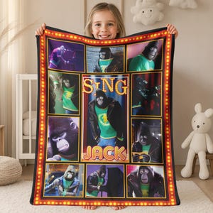 May include: A plush blanket featuring a collage of images from the animated movie "Sing." The design includes a central image of a gorilla character named Jack, surrounded by other scenes. The border is black with a red and yellow marquee-style design.