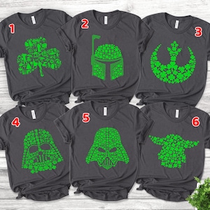 May include: Six dark gray t-shirts with green designs. The designs include a shamrock, a helmet, a symbol, and three character faces, all made of shamrocks. The shirts are short-sleeved.