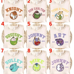 May include: Nine cream-colored t-shirts with different cartoon character designs. Each shirt features a character's name in a collegiate font, the text "EST. 2025", and a corresponding cartoon image. The shirts are arranged on a woven surface.