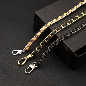 May include: Three chain straps with different finishes: one with a silver chain and brown leather, one with a gold chain and black leather, and one with a black chain and black leather.