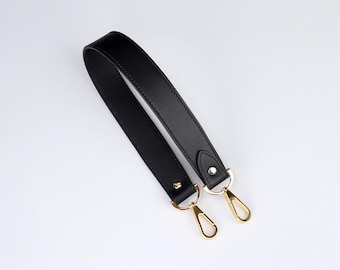 May include: Black leather shoulder strap with gold metal clasps. The strap is about 1 inch wide.